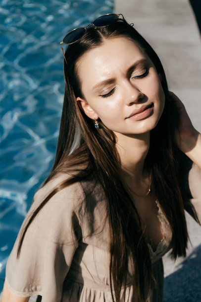 attrayant beau modèle de fille posant au soleil, sur le fond de l'eau, les yeux fermés
 - Photo, image