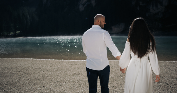 Hermosa pareja joven están caminando por el lago sosteniendo sus manos.4k
 - Imágenes, Vídeo