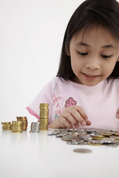 Little girl counts her coins on a table - Photo, Image