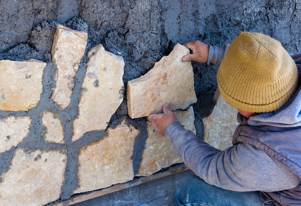  Trabajador pegado revestimiento de piedra en la fachada exterior
. - Foto, Imagen