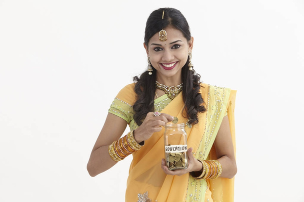Indian woman in glamorous traditional clothing holding a saving jar  - Foto, imagen