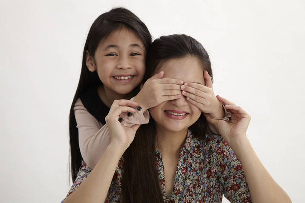 happy little girl cover her mother eyes for fun - Фото, изображение