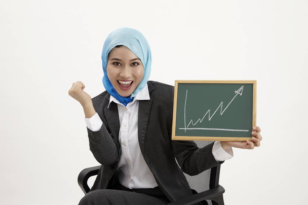 malay business woman sitting on office chair holding blackboard with chart raising - Photo, Image