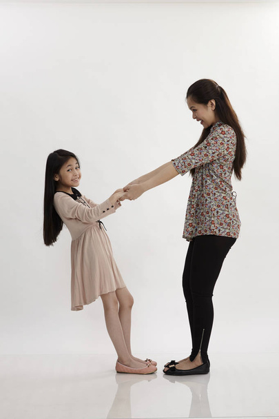 mother and daughter pulling each other posing in studio - Foto, imagen