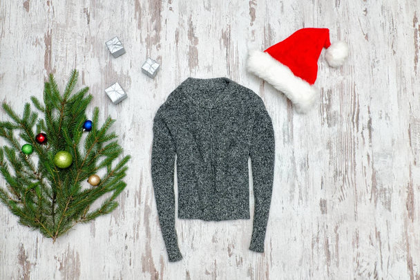 Gray sweater, Santa's hat and fir branch on a wooden background. - Fotografie, Obrázek