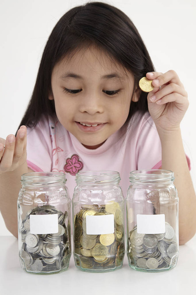 little with three saving jars with coins - Foto, immagini