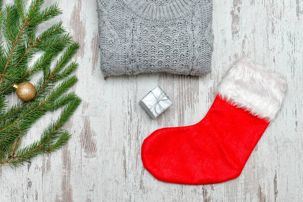 Red Christmas sock and a gray sweater. Decorated fir branch - Fotó, kép