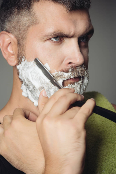 Man cut beard and mustache with razor and shaving brush - Foto, afbeelding