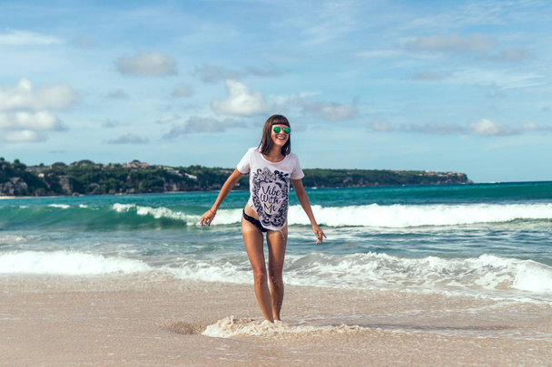 Beautiful young woman in sunglasses posing on the beach of a tropical island of Bali, Indonesia. - Фото, зображення