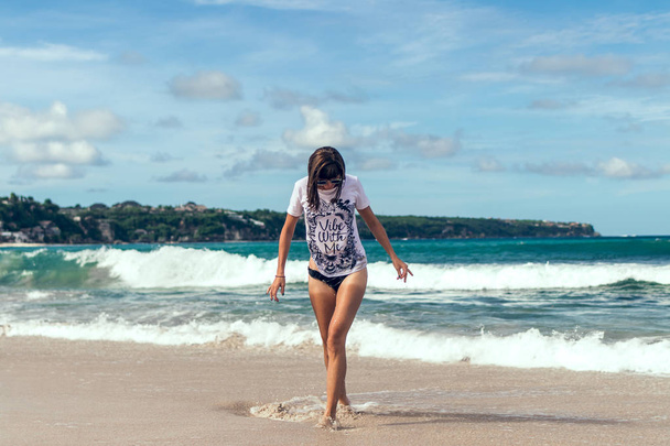 Bella giovane donna in occhiali da sole in posa sulla spiaggia di un'isola tropicale di Bali, Indonesia
. - Foto, immagini
