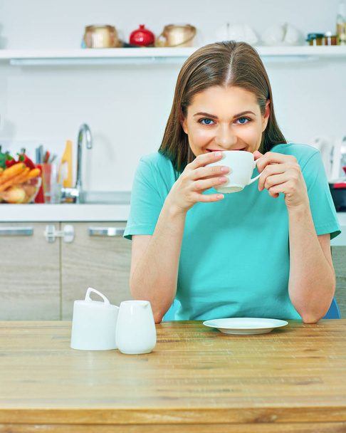 Smiling beautiful casual dressed woman drinking coffee in kitchen at home - Foto, immagini