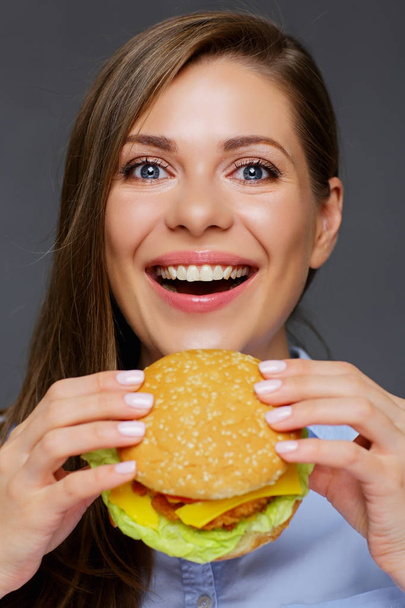 portrait of young smiling woman eating fast food burger  - 写真・画像