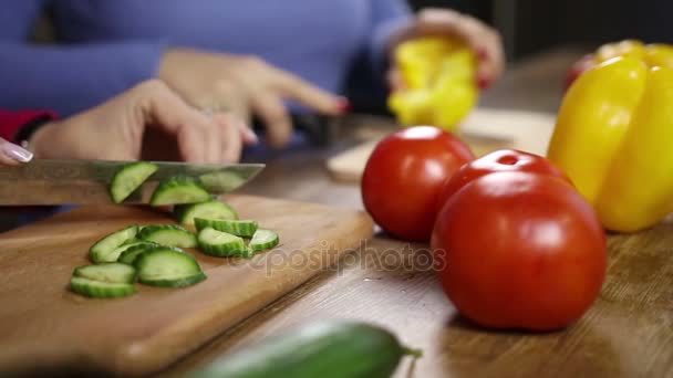 Naiset kädet pilkkovat vihanneksia keittiössä
 - Materiaali, video