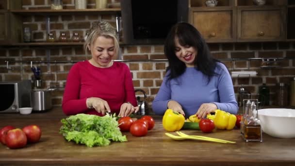 Mujeres sonrientes cortando verduras en la cocina
 - Metraje, vídeo