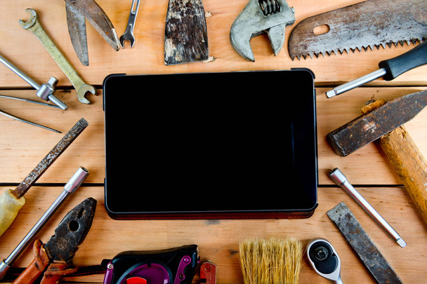 Tablet και παλιά εργαλεία σε ένα φυσικό ξύλινο υπόβαθρο. - Φωτογραφία, εικόνα