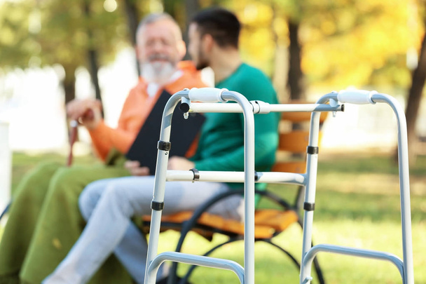 Young caregiver sitting with senior man  - Фото, зображення