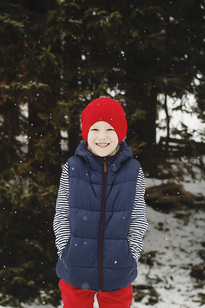 雪に覆われた冬の幸せな若い子供の山の上に立っています。 - 写真・画像