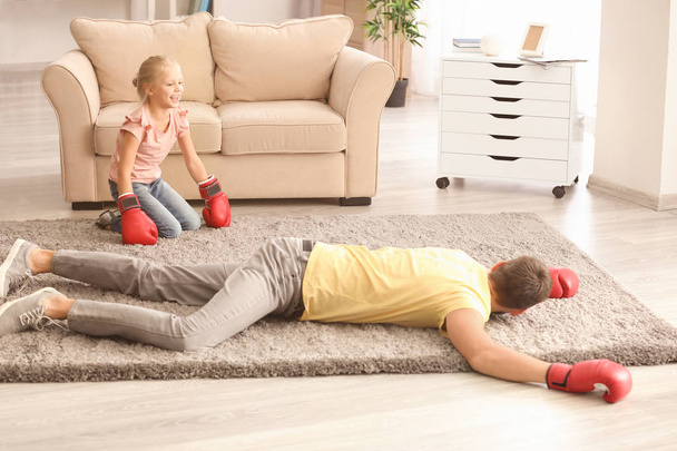Cute girl and her father in boxing gloves playing at home - Foto, Bild