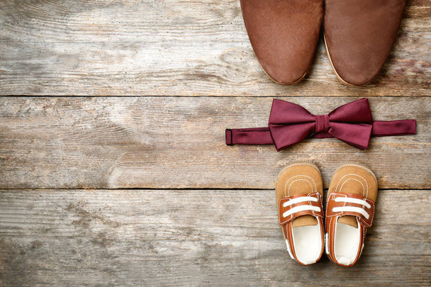 Bow tie, big and small shoes on wooden background. Father's day composition - Fotó, kép