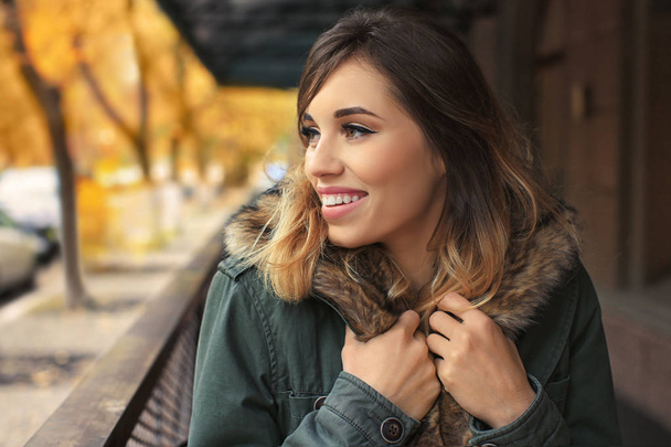 Attractive smiling woman in jacket with fur collar outdoors - Valokuva, kuva