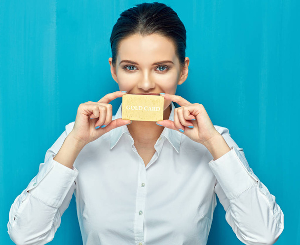 businesswoman holding credit card against lips on blue wall background  - Φωτογραφία, εικόνα