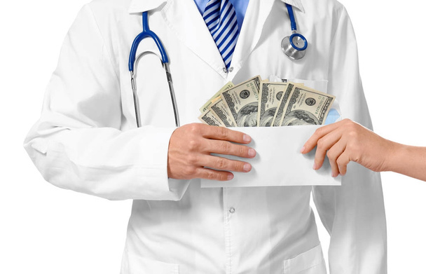 Woman giving envelope with bribe to doctor on white background, closeup - Foto, immagini
