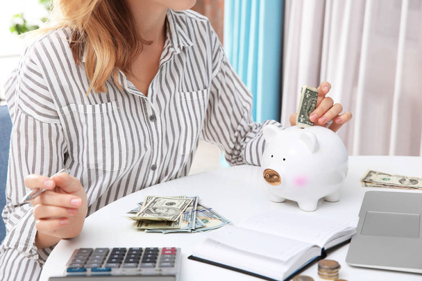Young woman putting money into piggy bank, closeup - Fotó, kép