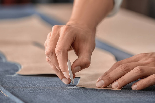 Young tailor working with sewing pattern, closeup - Foto, Imagen