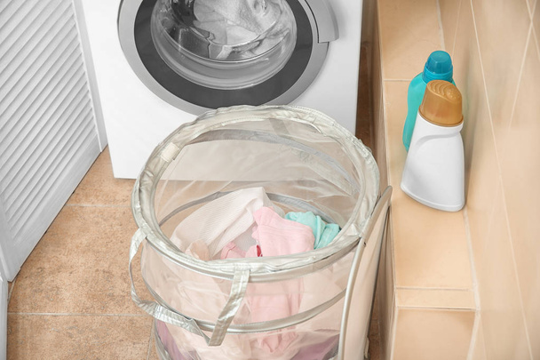 Basket with laundry near washing machine in bathroom - 写真・画像
