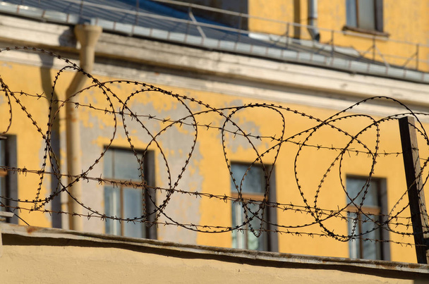 Drut kolczasty na ścianach więzienia. - Zdjęcie, obraz