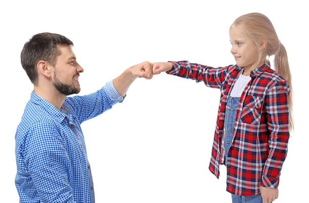 Schattig klein meisje en haar vader stoten vuisten op witte achtergrond - Foto, afbeelding