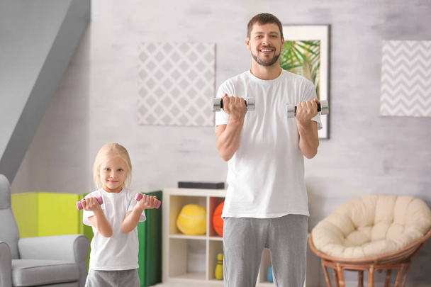 Cute girl and her father training with dumbbells at home - Φωτογραφία, εικόνα
