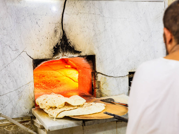 Imagen recortada del hombre horneando pan plano árabe tradicional en la panadería en el casco antiguo de Dubai
 - Foto, imagen