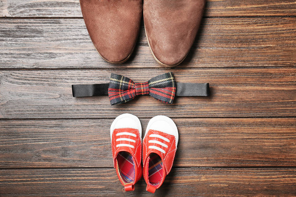 Bow tie, big and small shoes on wooden background. Father's day composition - Foto, Imagem