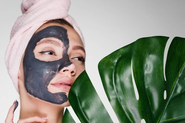 beautiful young girl takes care of herself, day spa, on face gray clay useful mask - 写真・画像
