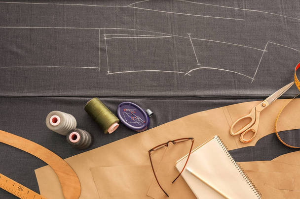 Grey fabric and sewing accessories on table, top view - 写真・画像