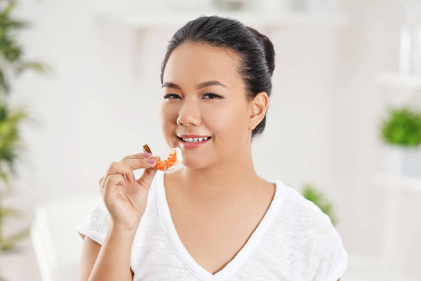 Beautiful Asian woman eating shrimp, indoors - Foto, Bild