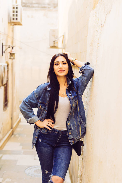 sexy beautiful black-haired girl is traveling in Baku, posing near beautiful architecture - Photo, Image