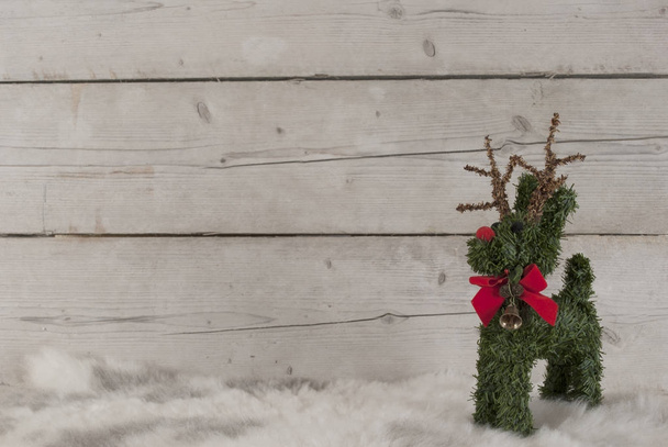 Christmas background, cute reindeer standing on sheepskin, on wooden backdrop - Photo, Image
