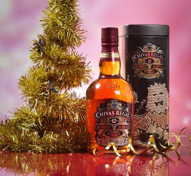 Whisky Chivas Regal a karácsonyfa és arany szalaggal. - Fotó, kép
