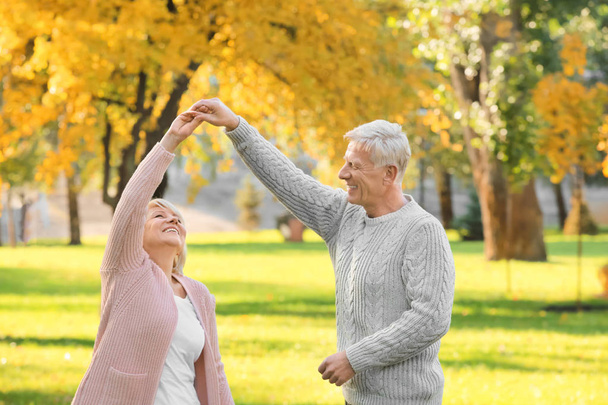 Cute elderly couple dancing in autumn park - Foto, imagen
