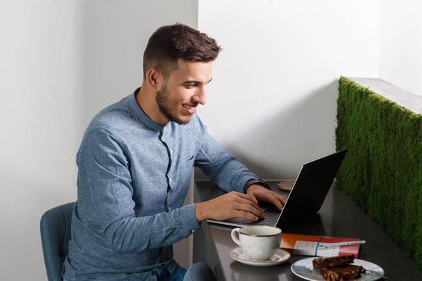Giovane uomo d'affari con laptop, caffè e snack. Lavorare dal concetto di casa. - Foto, immagini