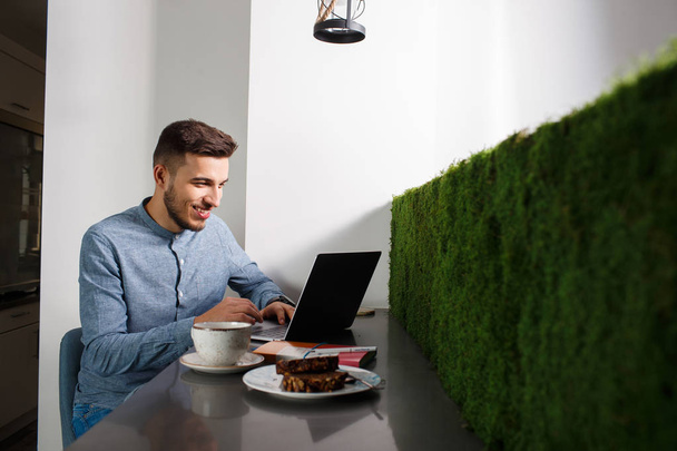 Young businessman with laptop, coffee and snacks - Photo, image