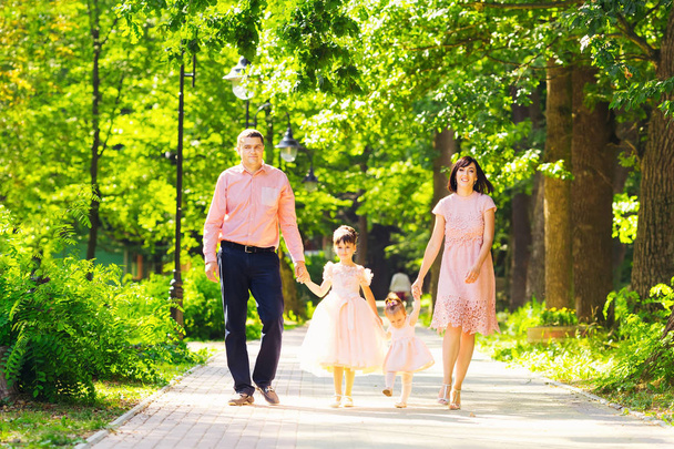 Père, mère et deux filles dans les vêtements de fête se promènent dans le parc par temps ensoleillé
 - Photo, image
