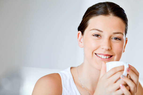Happy young woman with cup of tea or coffee at home - Fotó, kép