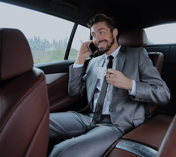 Happy young businessman using mobile phone in back seat of car - Φωτογραφία, εικόνα