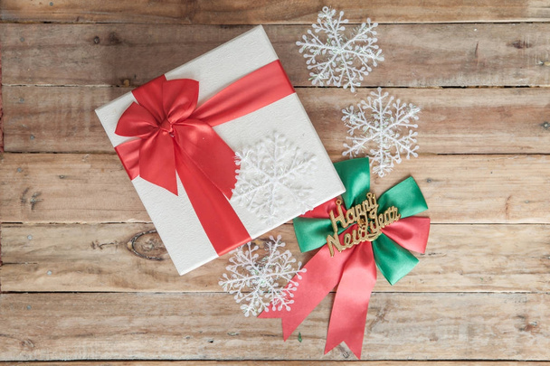 White gift box and red ribbon  on wood background with space - 写真・画像