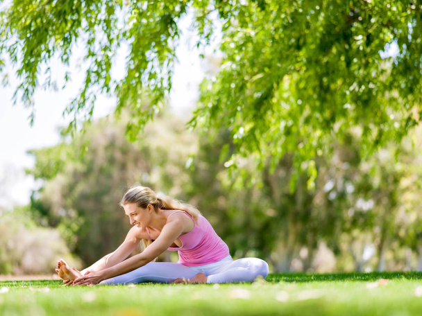 Young woman doing yoga in the park - Foto, imagen