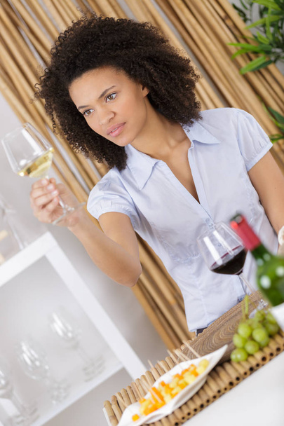 cheerful attractive brunette drinking white wine in her living room - Foto, imagen
