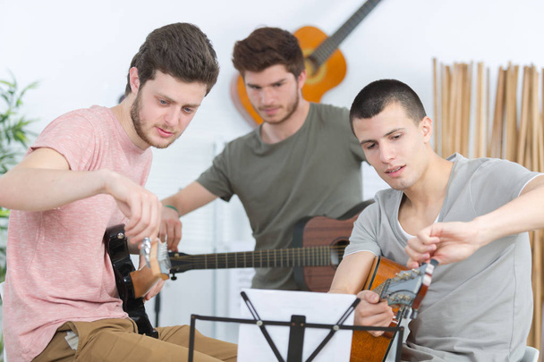 Young men tuning their guitars for rehearsal - Photo, image